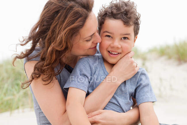 Mother and son sitting on beach — Stock Photo