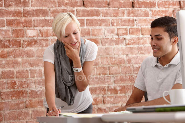 Dos colegas hablando en el escritorio - foto de stock