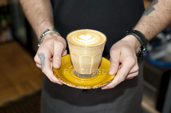 Manos de camarero café que sirve café con leche fresca en vidrio - foto de stock