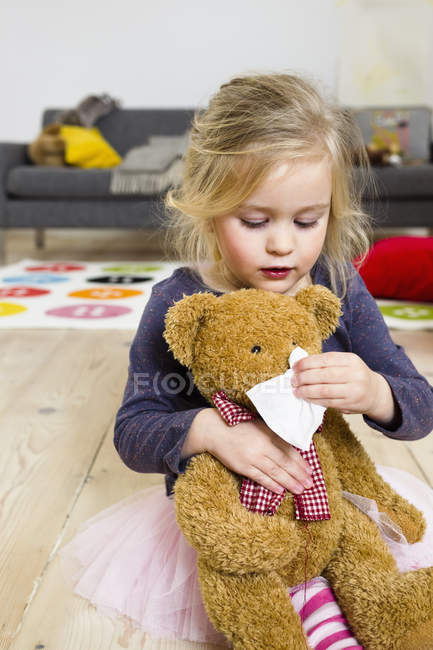 Girl playing mummy to bear — Stock Photo