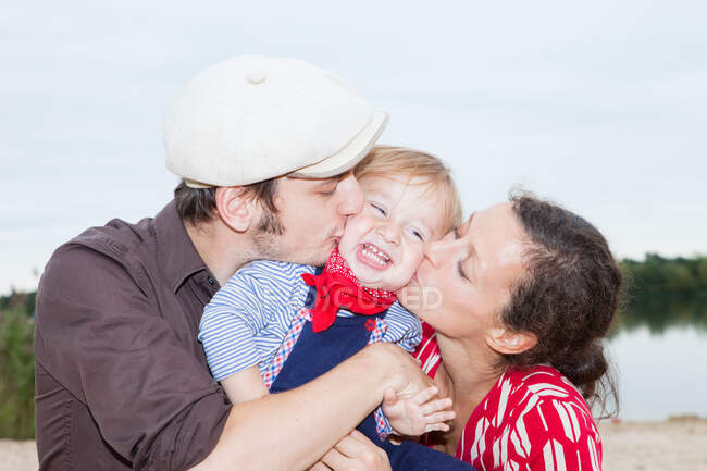 Casal beijando seu filho jovem em suas bochechas — Fotografia de Stock