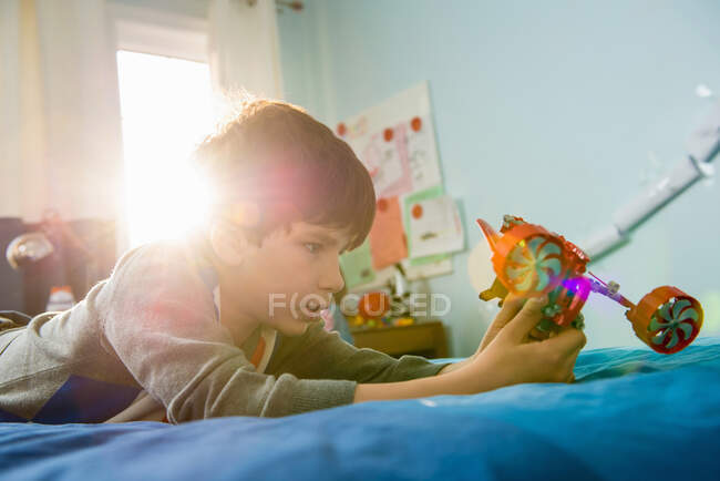 Boy lying on bed with toy — Stock Photo