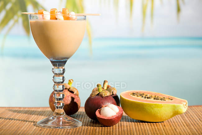 Glass of cocktail with tropical fruit in sunlight — Stock Photo