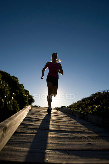 Junge Frau läuft Boardwalk hinunter — Stockfoto