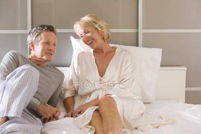 Пара сидить на ліжку розмовляє — стокове фото