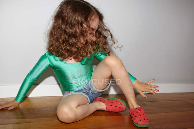 Bambino sul pavimento guardando le unghie delle dita — Foto stock