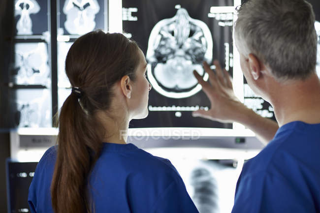 Male and female radiologists looking at brain scans — Stock Photo