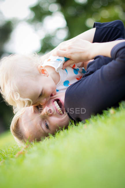 Mère et bébé jouant dans l'herbe — Photo de stock