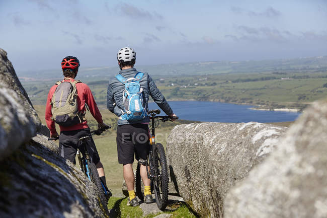 Велосипедисти з велосипедами на скелястому вилові — стокове фото