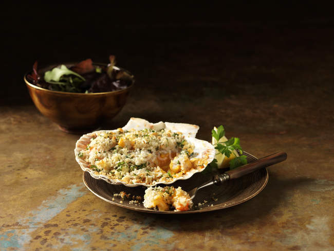 Натюрморт из лангустина и креветок пекут в ракушке со смешанным салатом — стоковое фото
