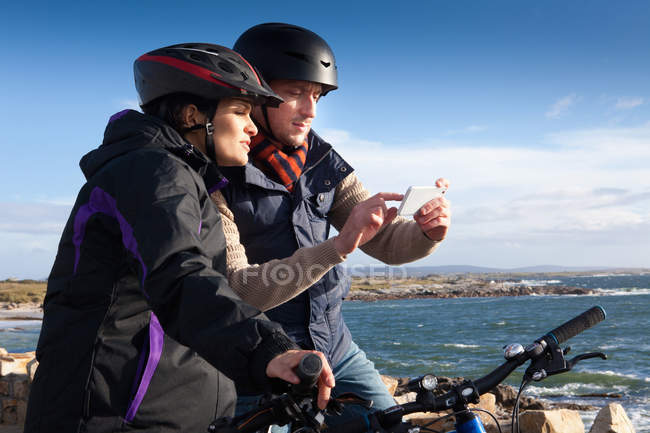 Pareja ciclista con smartphone, Connemara, Irlanda - foto de stock