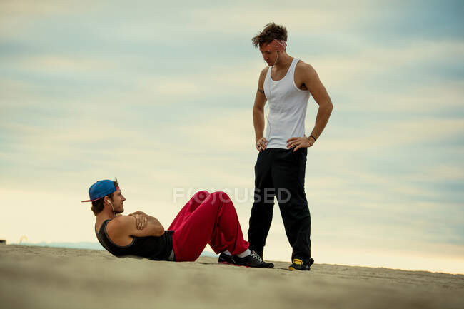 Hombres haciendo ejercicio juntos en la playa - foto de stock