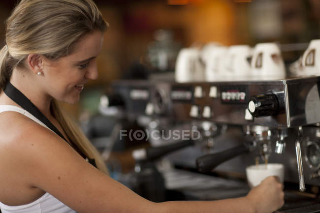 Junge Kellnerin bereitet Kaffee im Café zu — Stockfoto