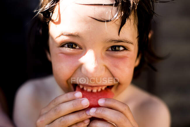 Niño feliz comiendo sandía en el día de verano - foto de stock