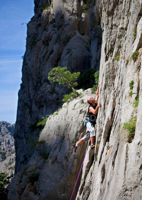 Escalador escalando roca cara - foto de stock