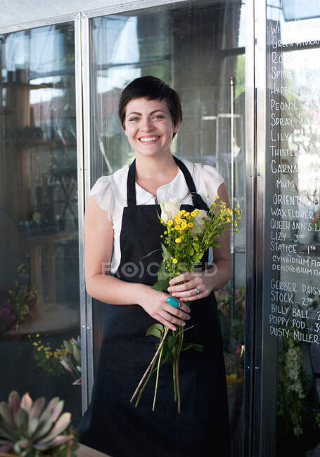 Portrait of florist holding bunch of flowers — Stock Photo