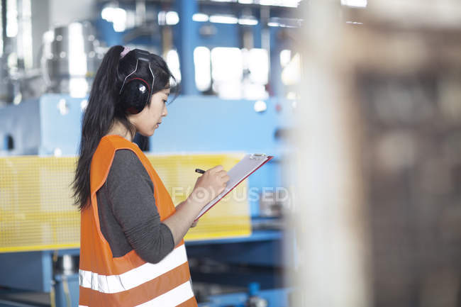 Techniker schreibt auf Klemmbrett in Fabrik — Stockfoto