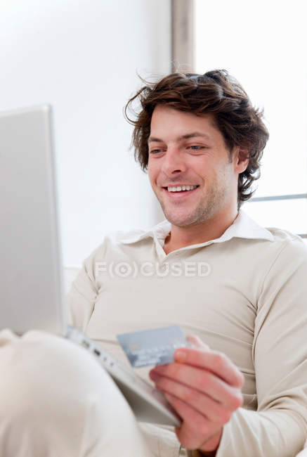 Hombre de compras en línea en sala de estar - foto de stock