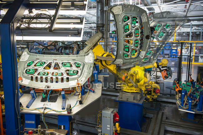 Robots manejando piezas de automóviles en fábrica de automóviles - foto de stock
