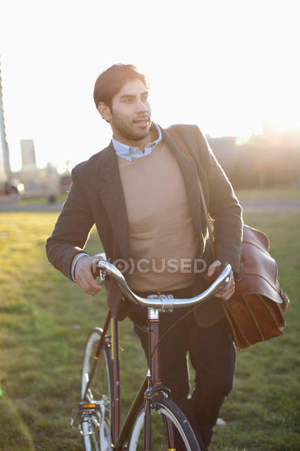 Чоловік штовхає велосипед у полі — стокове фото