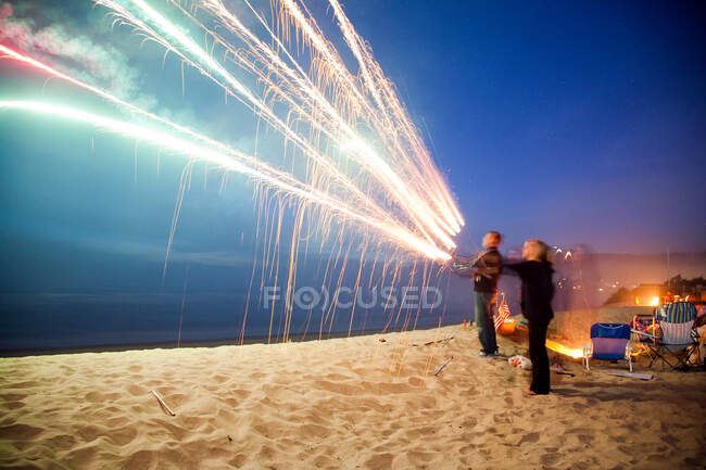 Menschen mit Feuerwerk am Strand in der Nacht — Stockfoto