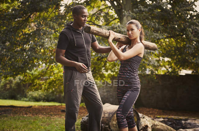 Woman with personal trainer explaining tree trunk shoulder lift in park — Stock Photo