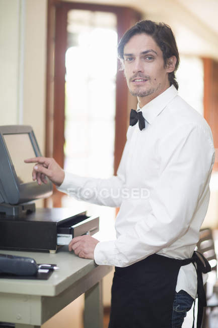Retrato de garçom usando tela sensível ao toque na caixa registradora no restaurante — Fotografia de Stock