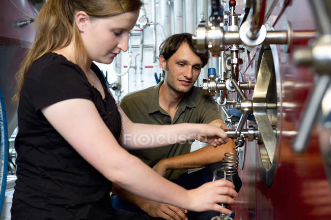 Female and male brewers working in beer brewhouse — Stock Photo