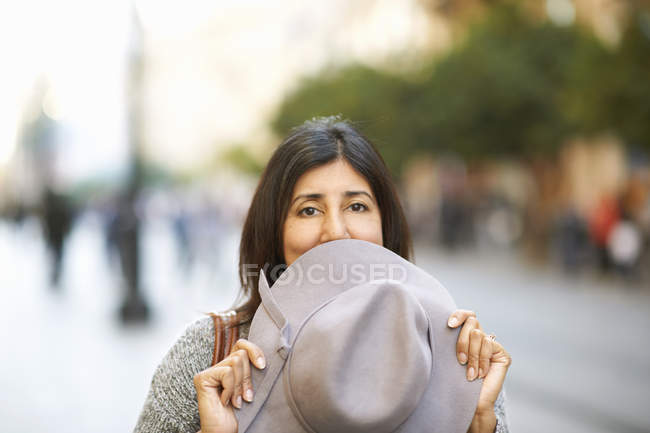 Donna che tiene il cappello sopra la bocca sulla strada — Foto stock