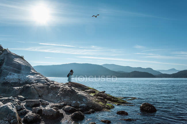 Woman on rocks, Whytecliff Park, Columbia Británica, Canadá - foto de stock