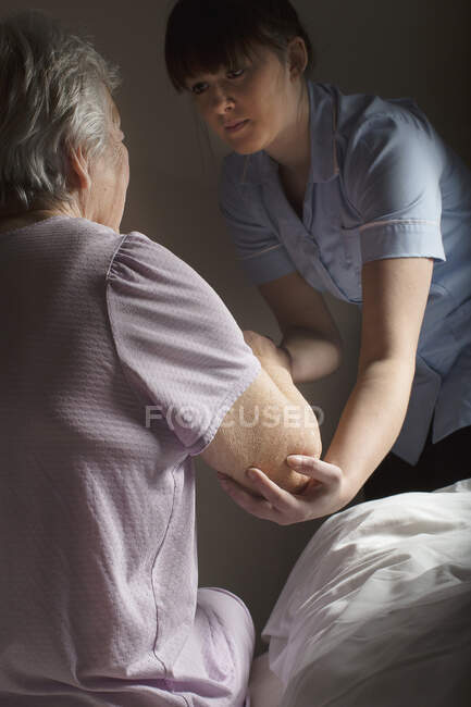 Personal care assistant helping senior woman to get up — Stock Photo