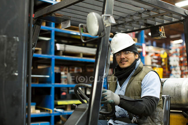 Worker driving forklift in metal plant — Stock Photo