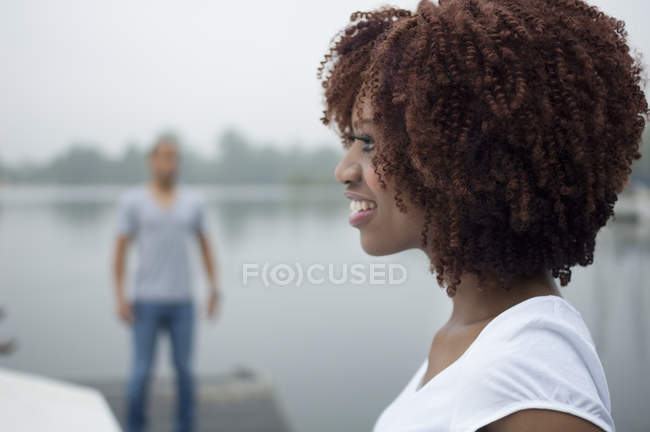 Портрет молодой женщины, улыбающейся с мужчиной на заднем плане — стоковое фото