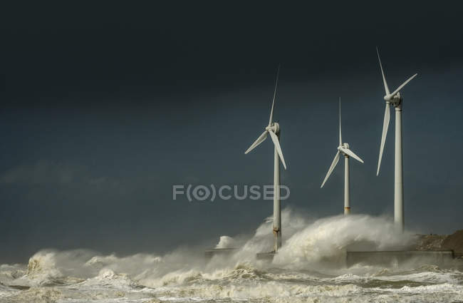 Turbine eoliche con onde di tempesta e nuvole sulla costa — Foto stock