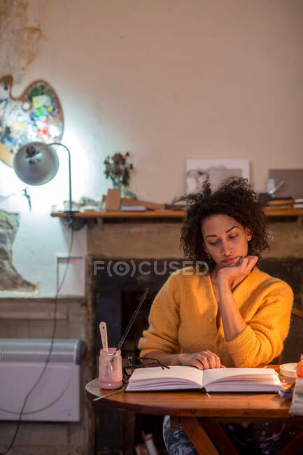 Woman reading book at desk — Stock Photo