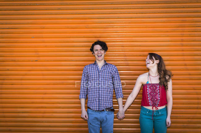 Portrait of couple in front of orange shutter — Stock Photo
