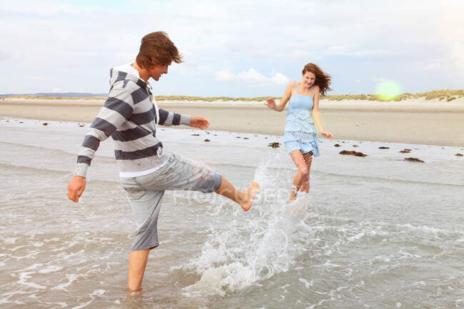 Young couple playing in the surf — Stock Photo
