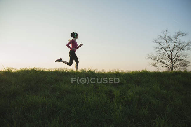 Joven corredora silueta en la colina - foto de stock
