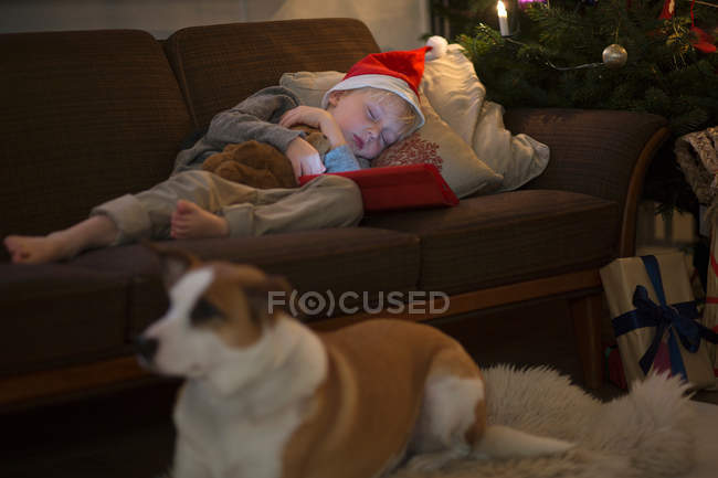 Menino de chapéu de Santa dormindo no sofá — Fotografia de Stock