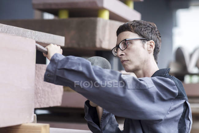 Каменщик с зубилом и молотком на каменном блоке — стоковое фото