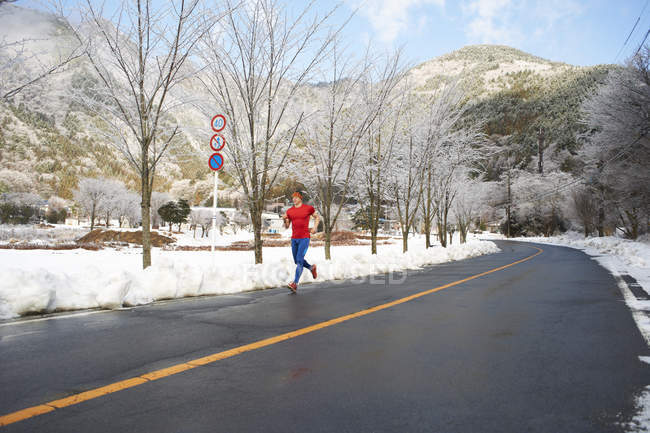 Männlicher Läufer läuft im Winter auf der Straße, Lake kawaguchiko, Mount fuji, Japan — Stockfoto