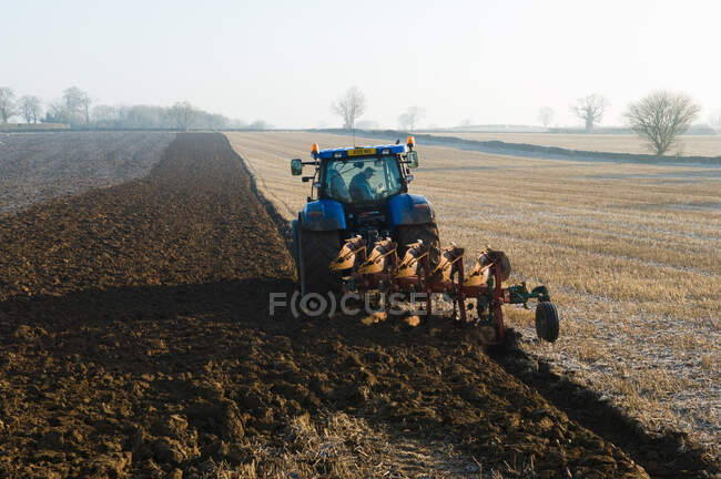 Трактор вспахивает землю поля — стоковое фото