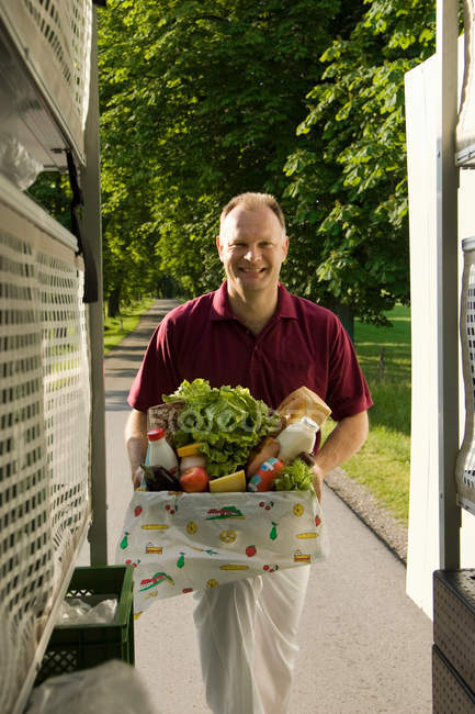 Smiling deliveryman with a box of groceries — Stock Photo