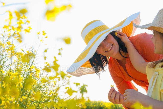 Girl putting flower in mothers hair — Stock Photo