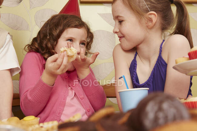 Girl eating party food with friend — Stock Photo