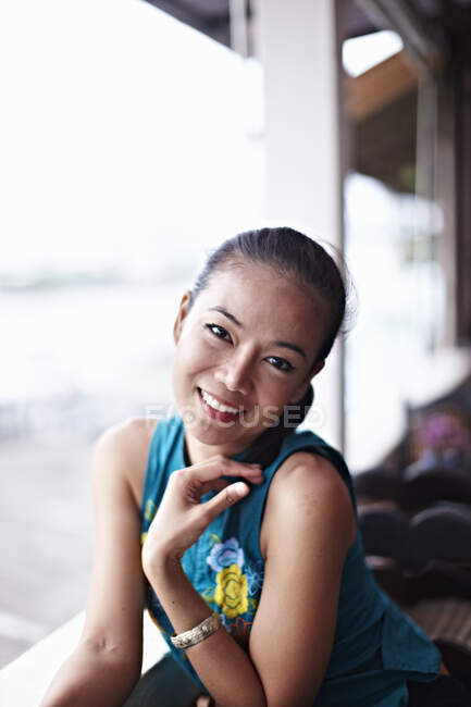 Donna sorridente seduta vicino alla finestra — Foto stock
