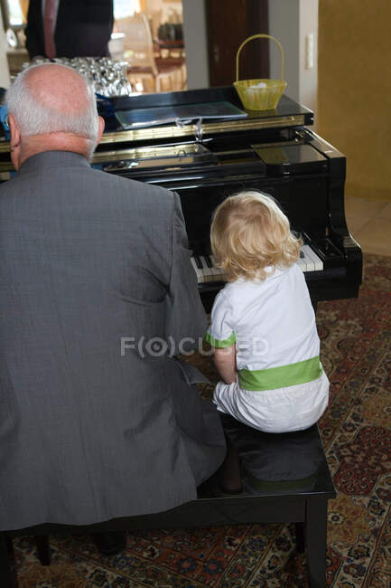 Jeune garçon joue du piano avec grand-père — Photo de stock
