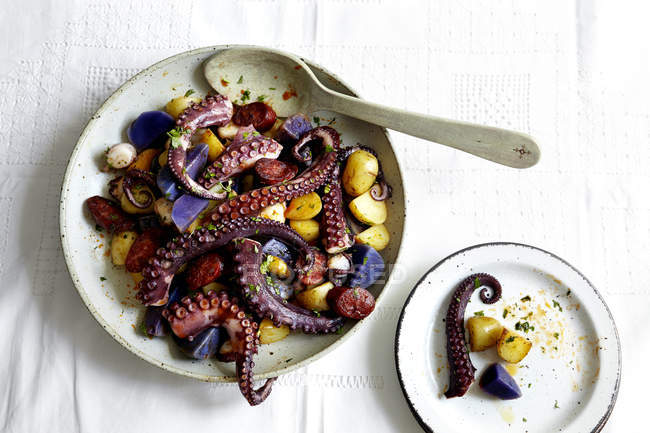 Tigela de tentáculos de polvo e batatas com colher na mesa — Fotografia de Stock