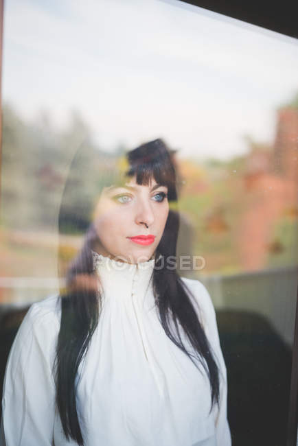 Молода жінка дивиться з вікна — стокове фото