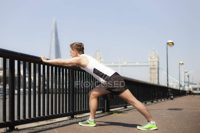 Runner stretching on riverfront, Wapping, London — Stock Photo